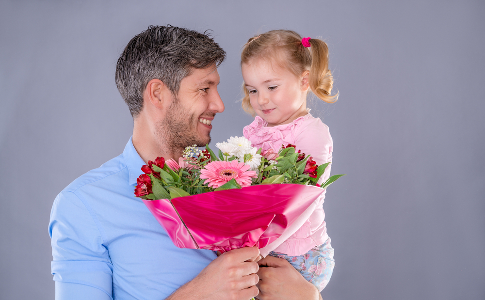 Дочка с папой поздравляют маму. Мужчина с цветами и дочкой. Папа дарит цветы. Папа дарит дочери цветы. Паа дарит дочери цветы.